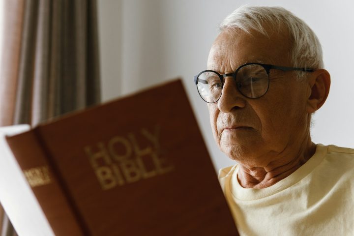 Elderly man reading holy bible at home
